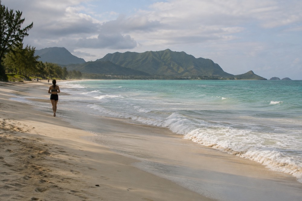 A wide view of the Kailua shoreline on Oahu with turquoise water and green ridges behind the beach