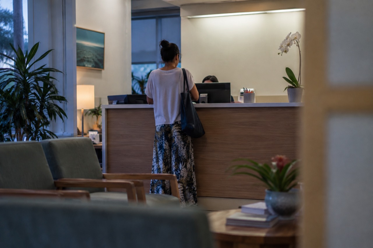 A quiet medical clinic reception desk in Honolulu with a visitor speaking to staff
