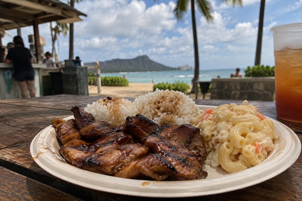 A plate lunch with rice and macaroni salad on a table at an open-air food counter on Oahu