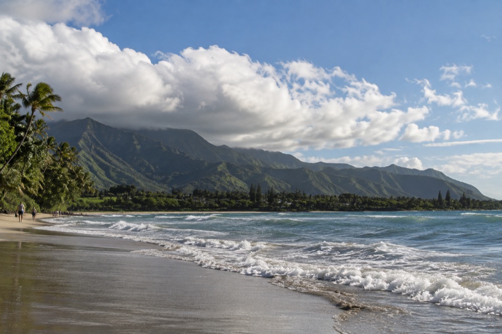 Trade wind clouds moving across a green Oahu valley toward the sea