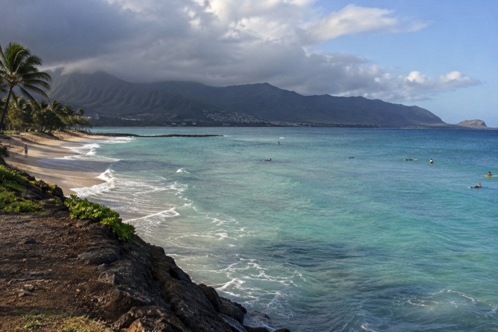 Rain clouds passing over the windward Koʻolau mountains while the coast stays in sunlight