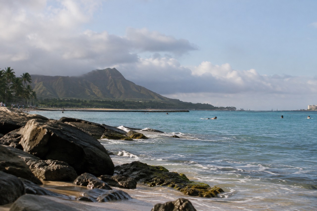 Clouds resting over green Oahu ridges with a calm blue ocean beyond