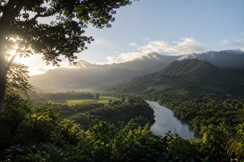 A quiet green valley on Kauai with mist on the ridgeline above a winding river