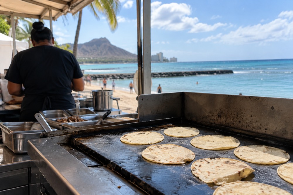 Fresh corn tortillas warming on a griddle in a small open kitchen