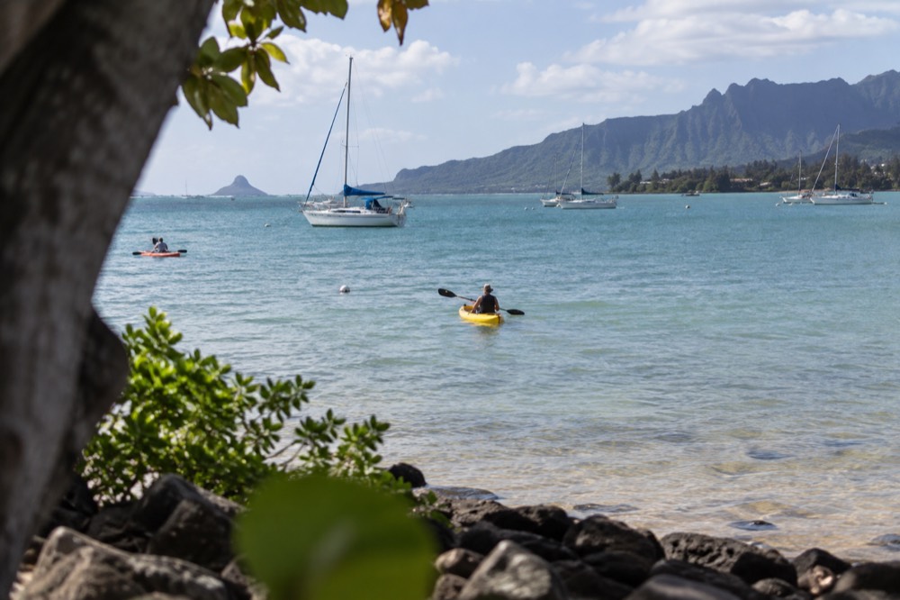 Sailboats and kayaks on Kāneʻohe Bay with the Mōkapu Peninsula visible across the water