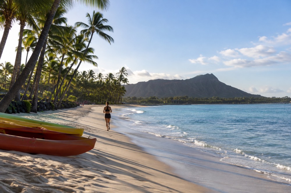 A calm morning at a windward Oahu beach with kayaks resting on white sand near palm trees