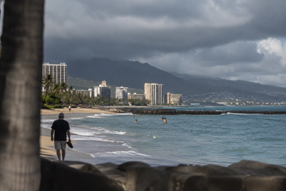 Dark rain clouds passing over the Koʻolau mountains above Honolulu, with sunlit buildings below