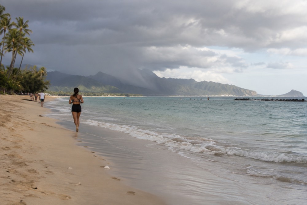 A rain shower falling over the green ridges of the Koʻolau range while the Honolulu coastline stays in sunshine