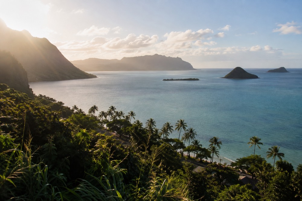 A turquoise bay on Oahu's windward coast with offshore islands and palm trees along the shore