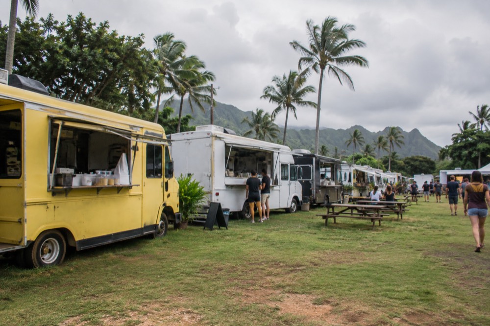 Food trucks lined up in a grassy lot on Oahu's North Shore