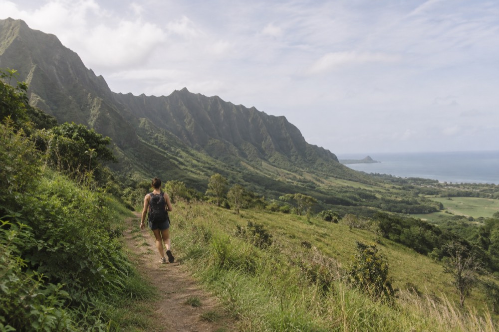 Green Kualoa valley ridges rising above the windward Oahu coast with the ocean in the distance