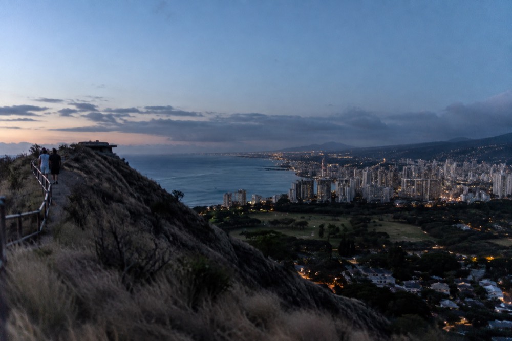 Aerial view of the Diamond Head crater rim rising above Honolulu rooftops toward the ocean