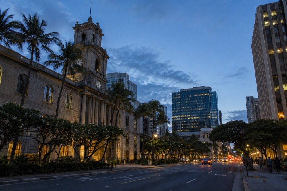 Historic stone buildings and modern office towers side by side on a downtown Honolulu street