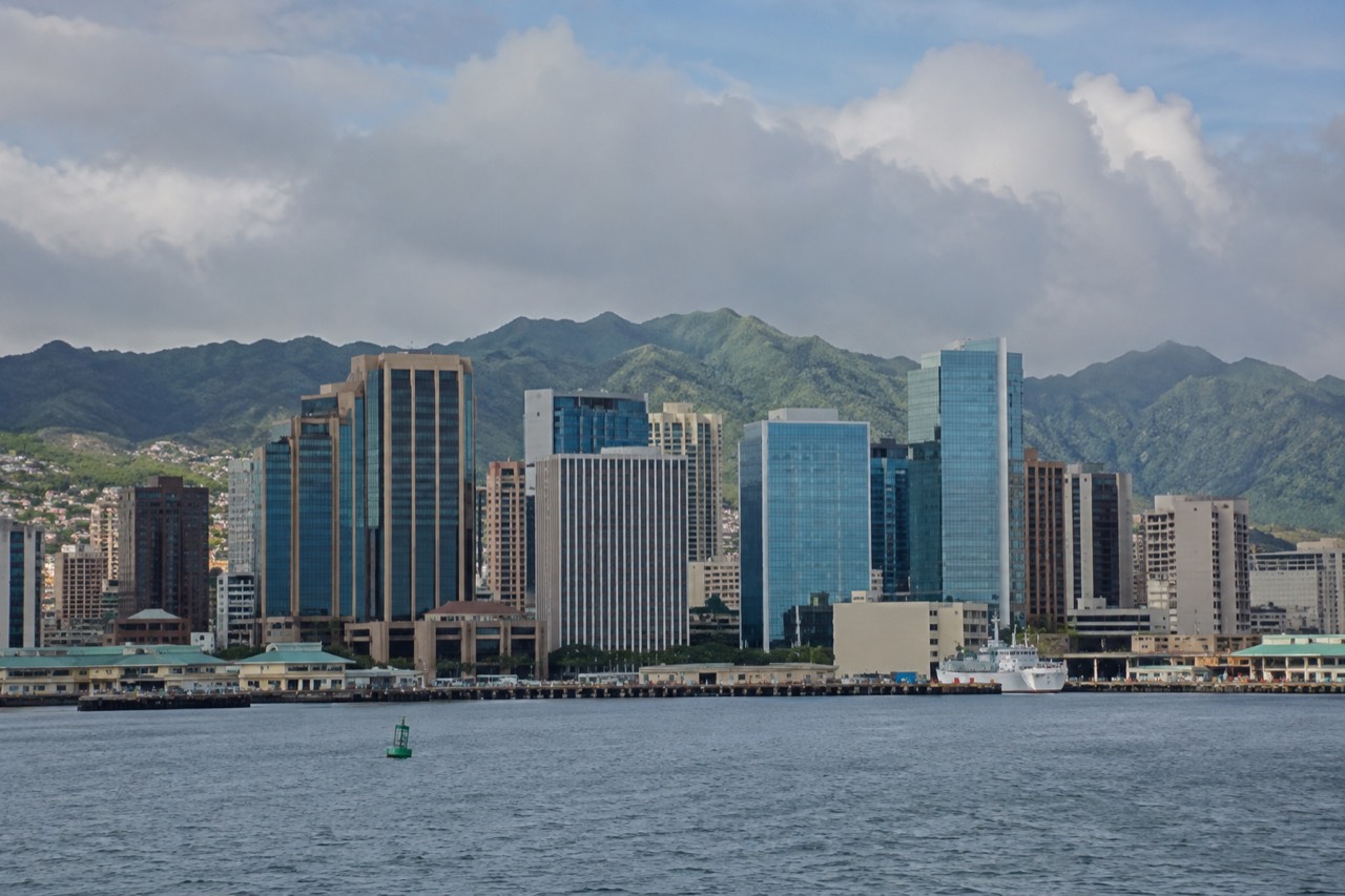 High-rise office towers of downtown Honolulu seen from across the harbor, with the Koʻolau mountains behind