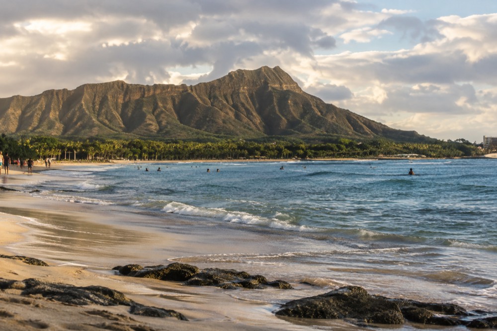 Waikīkī Beach at late afternoon with Diamond Head in the distance and calm water along the shore
