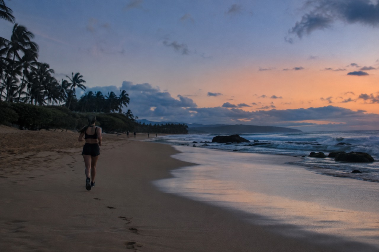 A wide sandy beach on Oahu's North Shore with golden evening light over calm water