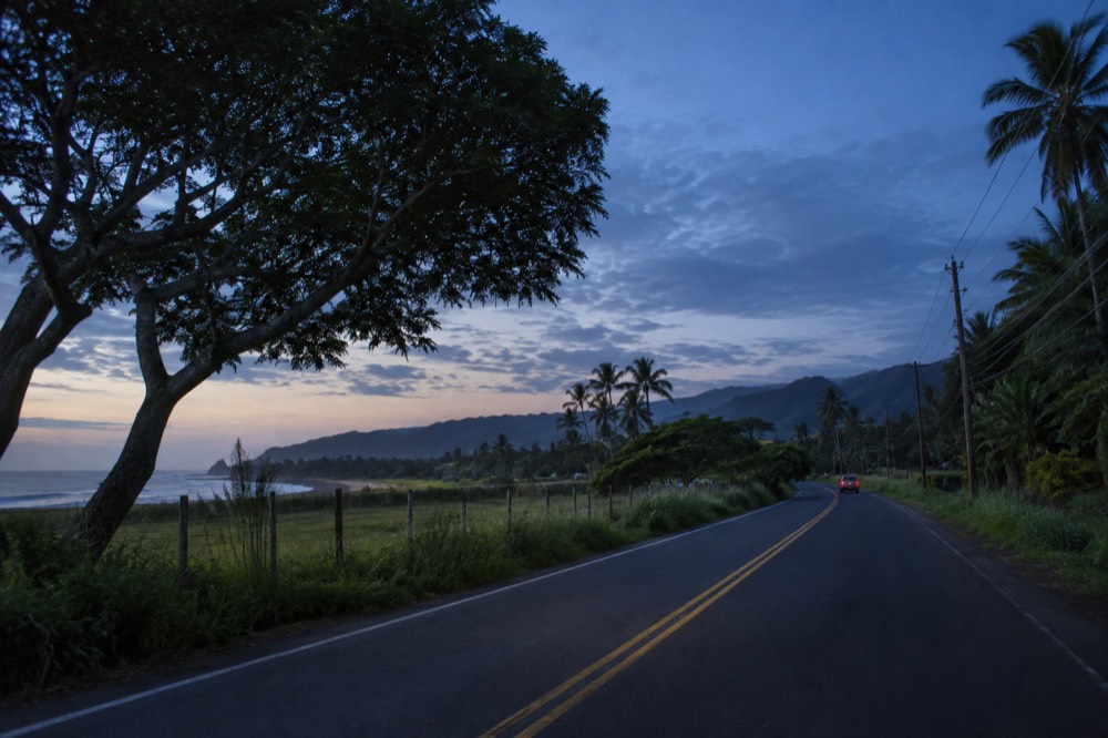 A quiet two-lane road through green countryside on Oahu's North Shore