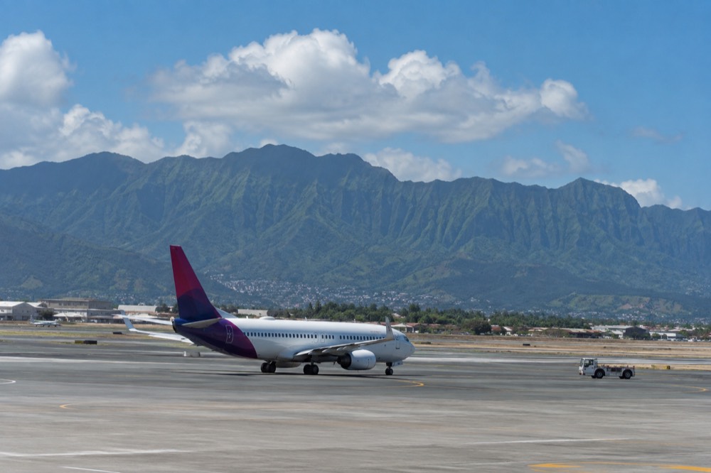 A interisland passenger jet on the tarmac at Honolulu airport with the Koʻolau mountains behind it