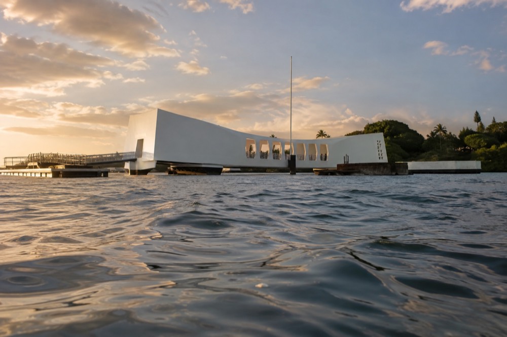 The white USS Arizona Memorial building seen from across the water at Pearl Harbor