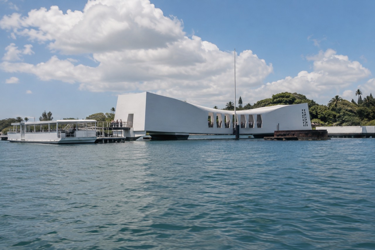 The USS Arizona Memorial structure standing above the water at Pearl Harbor with boats moored nearby