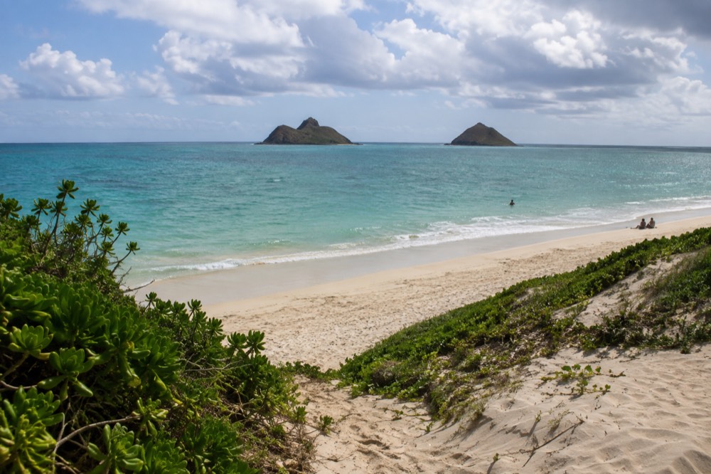 A quiet stretch of Kailua Beach with the Mokulua islands offshore under scattered clouds
