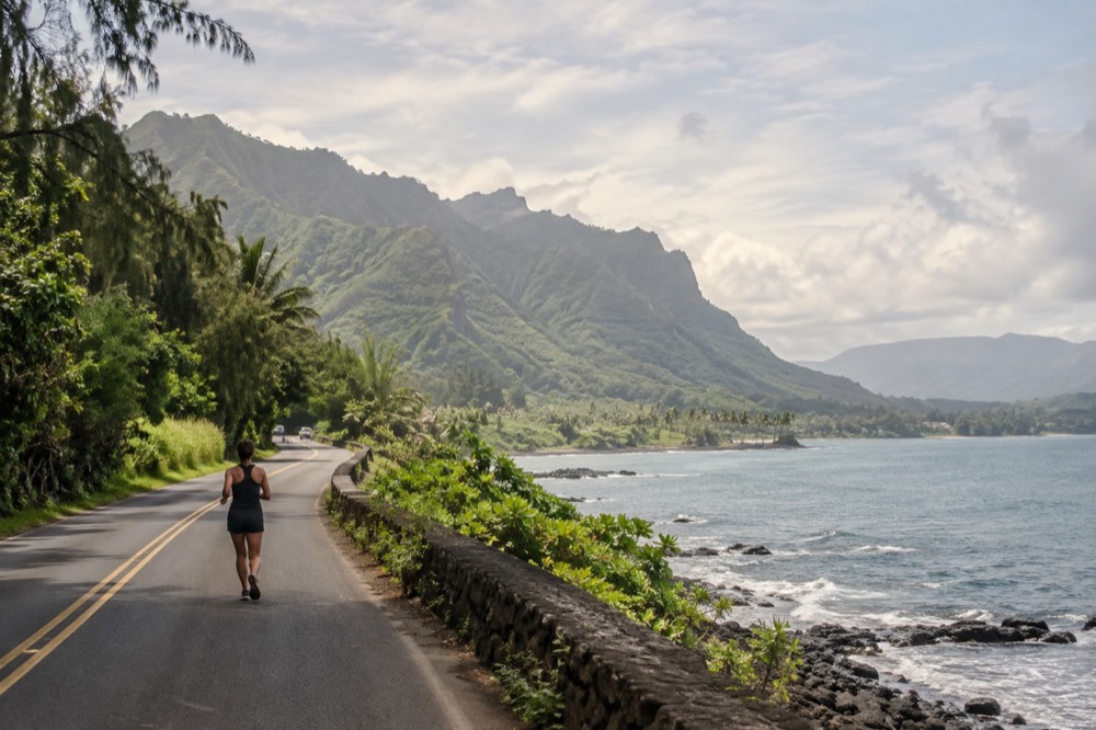 A quiet two-lane road along the green windward coast of Oahu with the ocean beyond