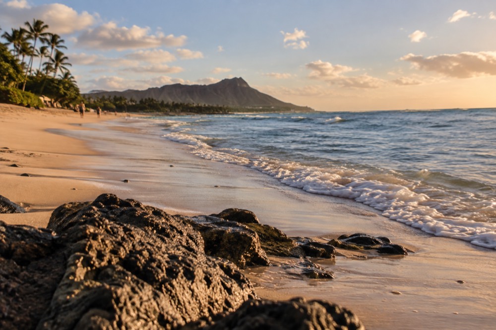 A quiet morning at a windward Oahu beach with a long curve of pale sand and small waves