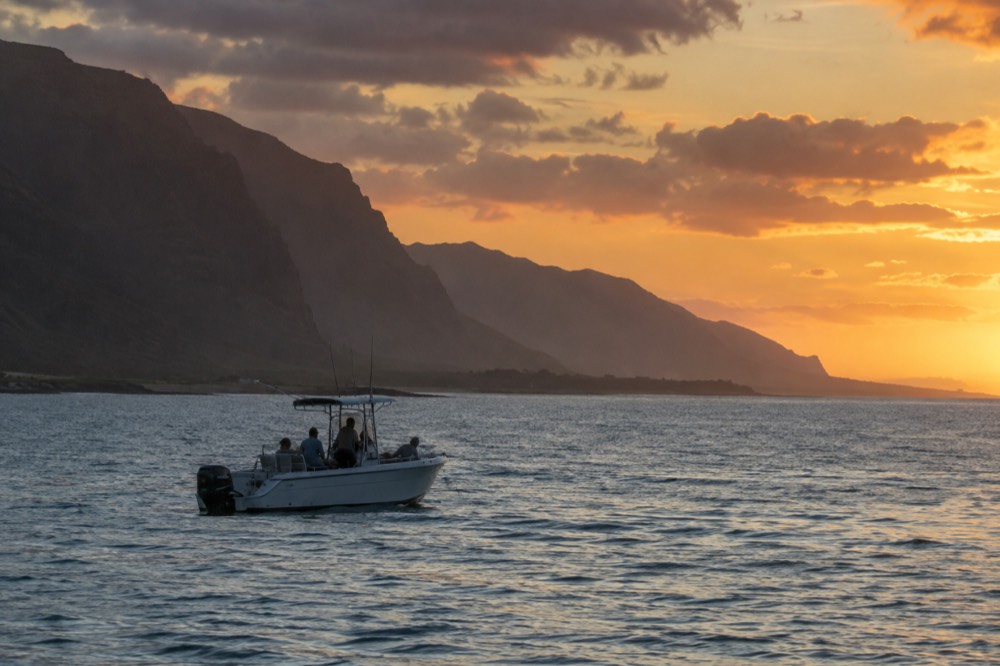 A small boat with passengers looking out at calm ocean water near the Waianae coast