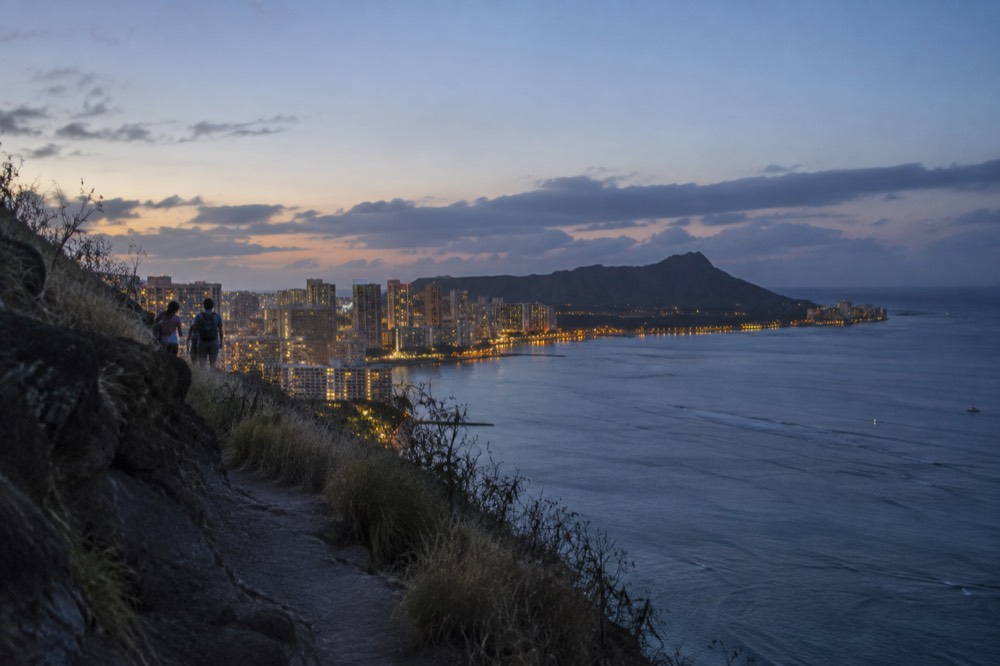 Evening lights along the Waikiki beachfront with the outline of Diamond Head in the fading light
