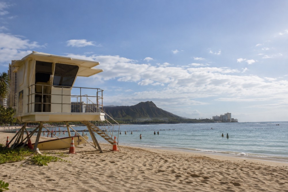 A lifeguard tower overlooking a calm swimming beach in Waikiki on a sunny morning