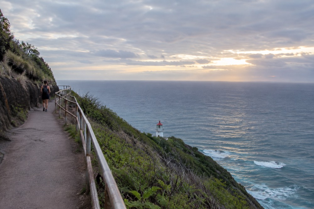A paved coastal trail above a lighthouse on Oahu's eastern shore at dawn