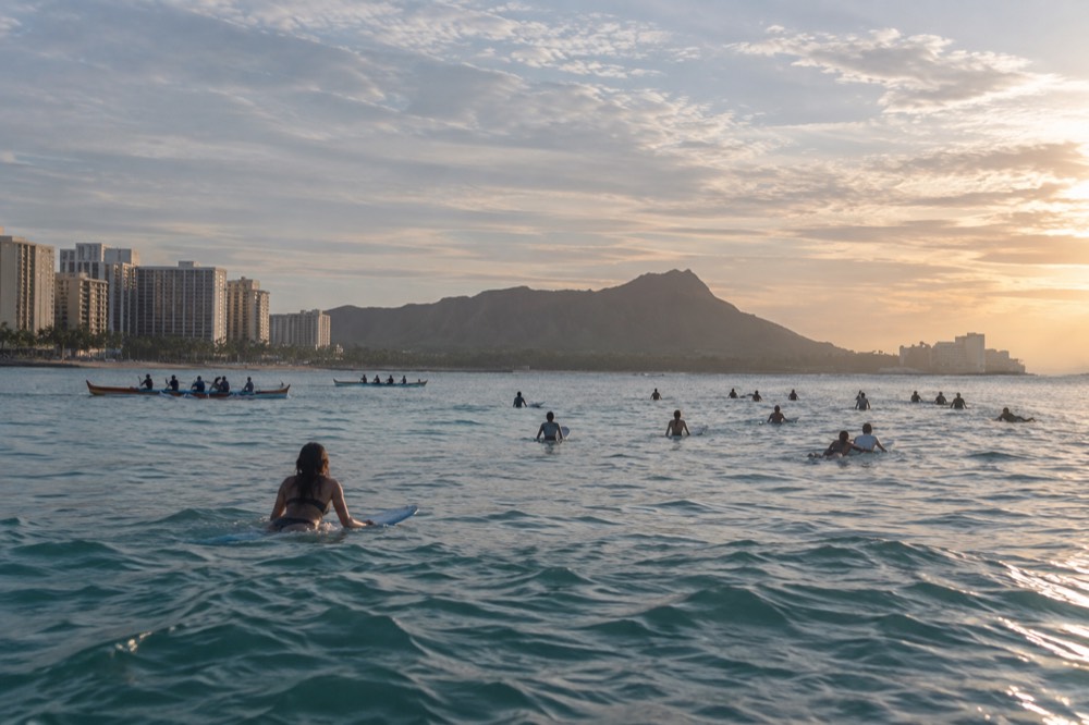 Long line of surfers waiting in the Waikiki lineup at sunrise with <a href=