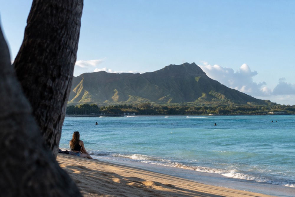 A green mountain ridge rising behind a calm Hawaiian beach with turquoise water