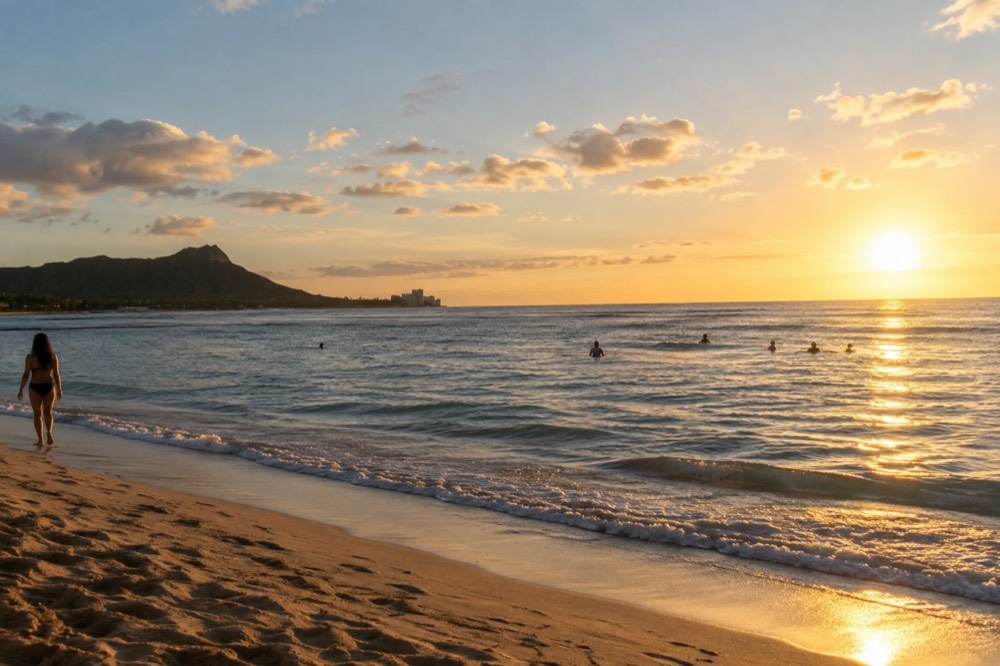 Golden evening light over a calm south-facing beach with small waves breaking on a reef
