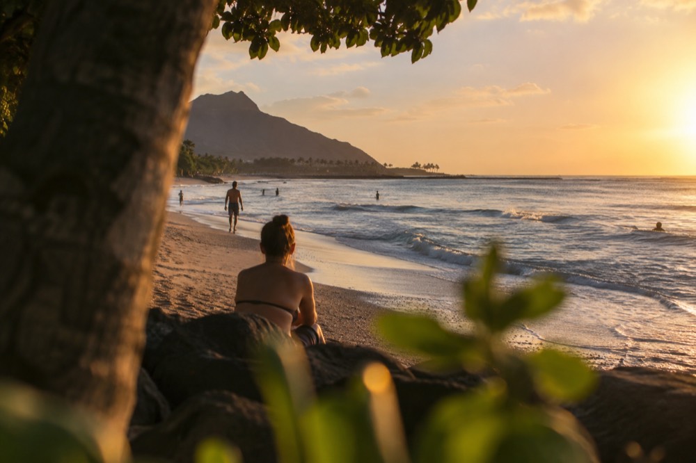 A calm Oʻahu beach in the late afternoon with gentle waves reaching the sand