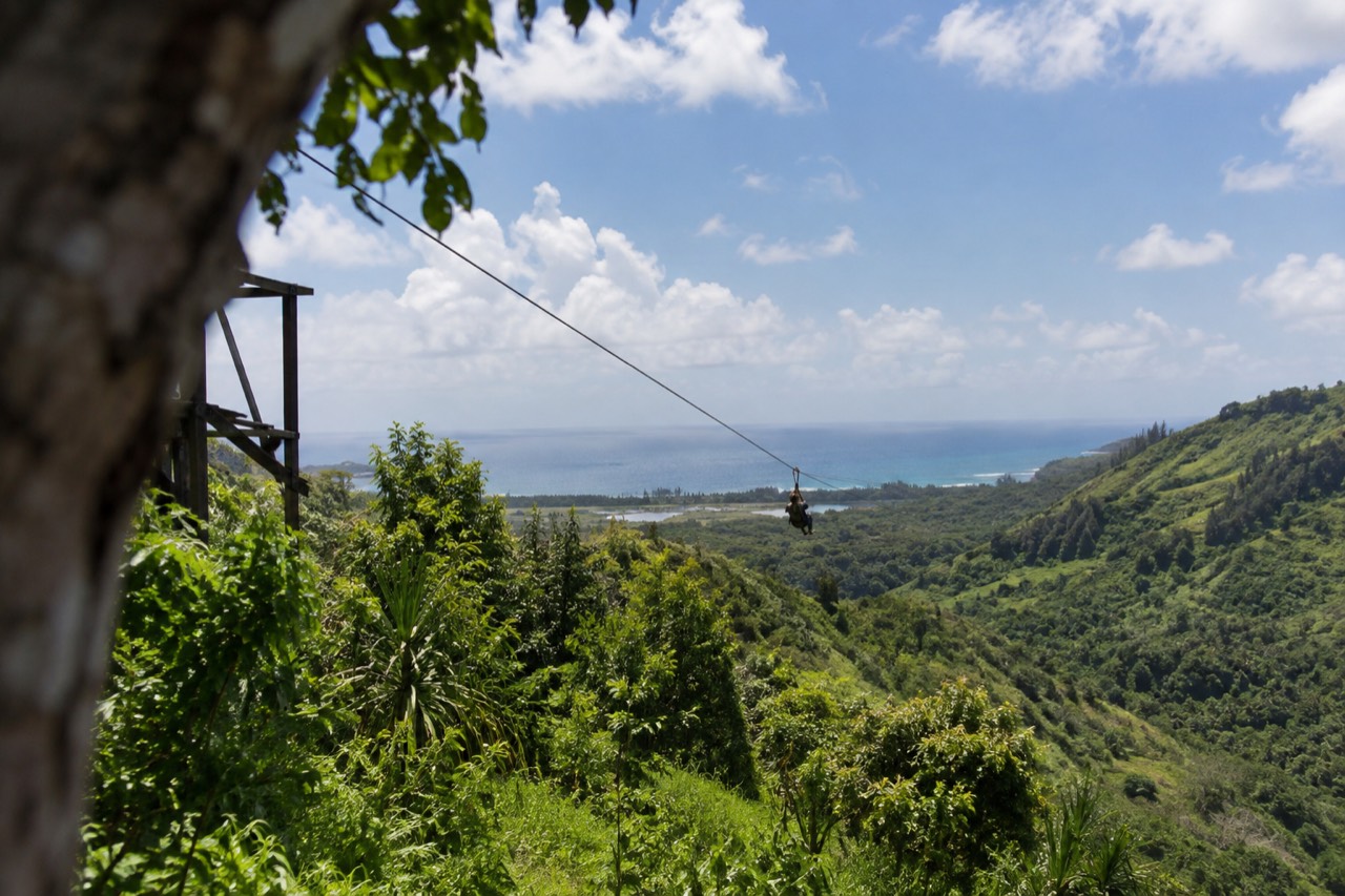 A zipline cable stretching over green ridges on Oahu's North Shore under a bright sky