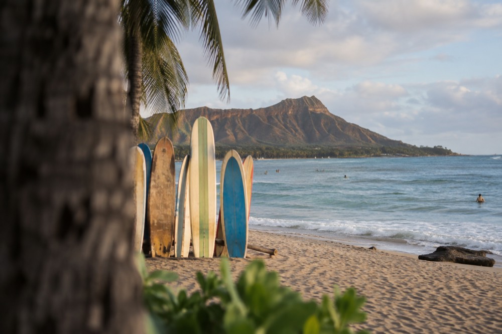 Longboards resting upright in the sand at Waikiki Beach with Diamond Head in the distance