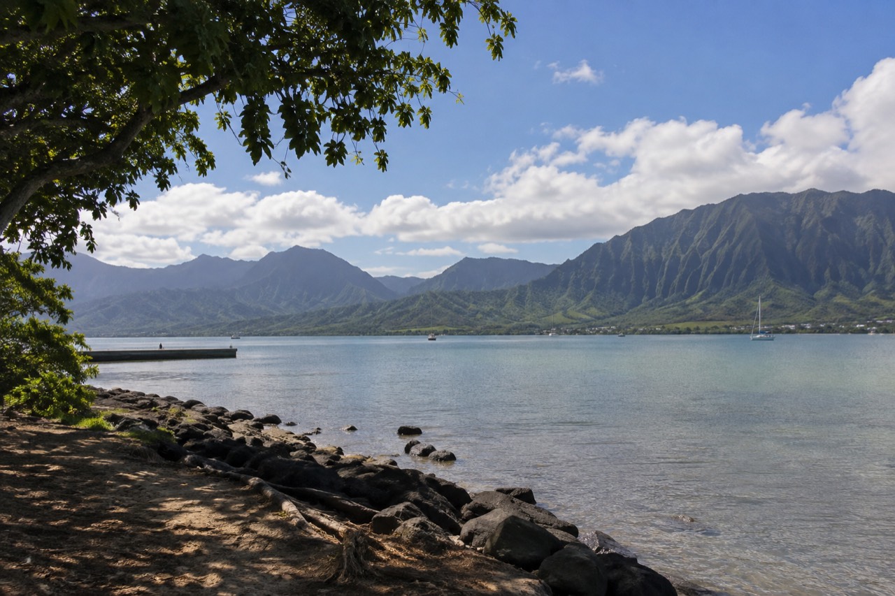 A view of Oahu's windward coast with green mountains meeting a calm bay