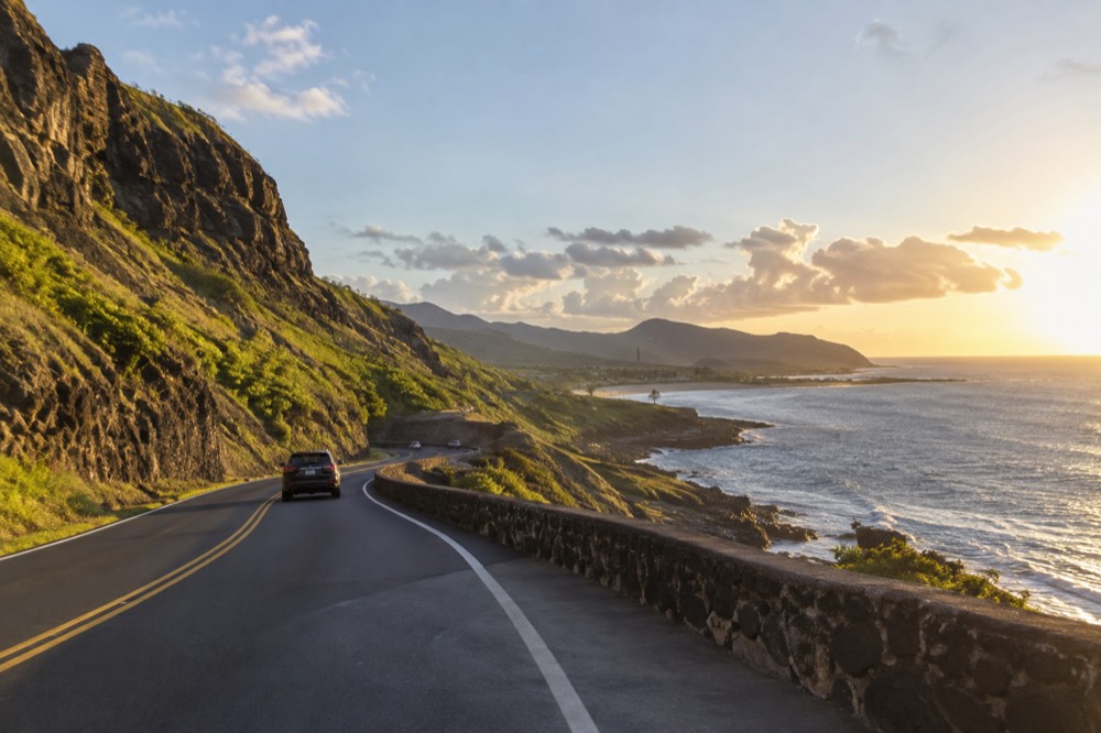 A coastal road on Oahu winding past green cliffs toward the ocean