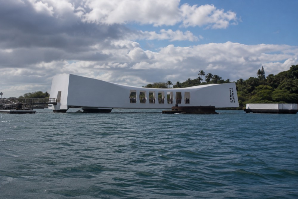 The white USS Arizona Memorial structure sitting low over the water at Pearl Harbor