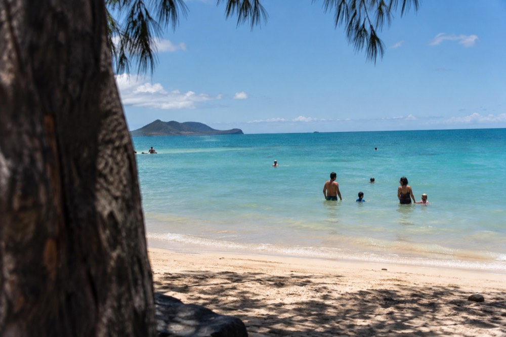 A family with young children wading in calm shallow water at Kailua Beach Park