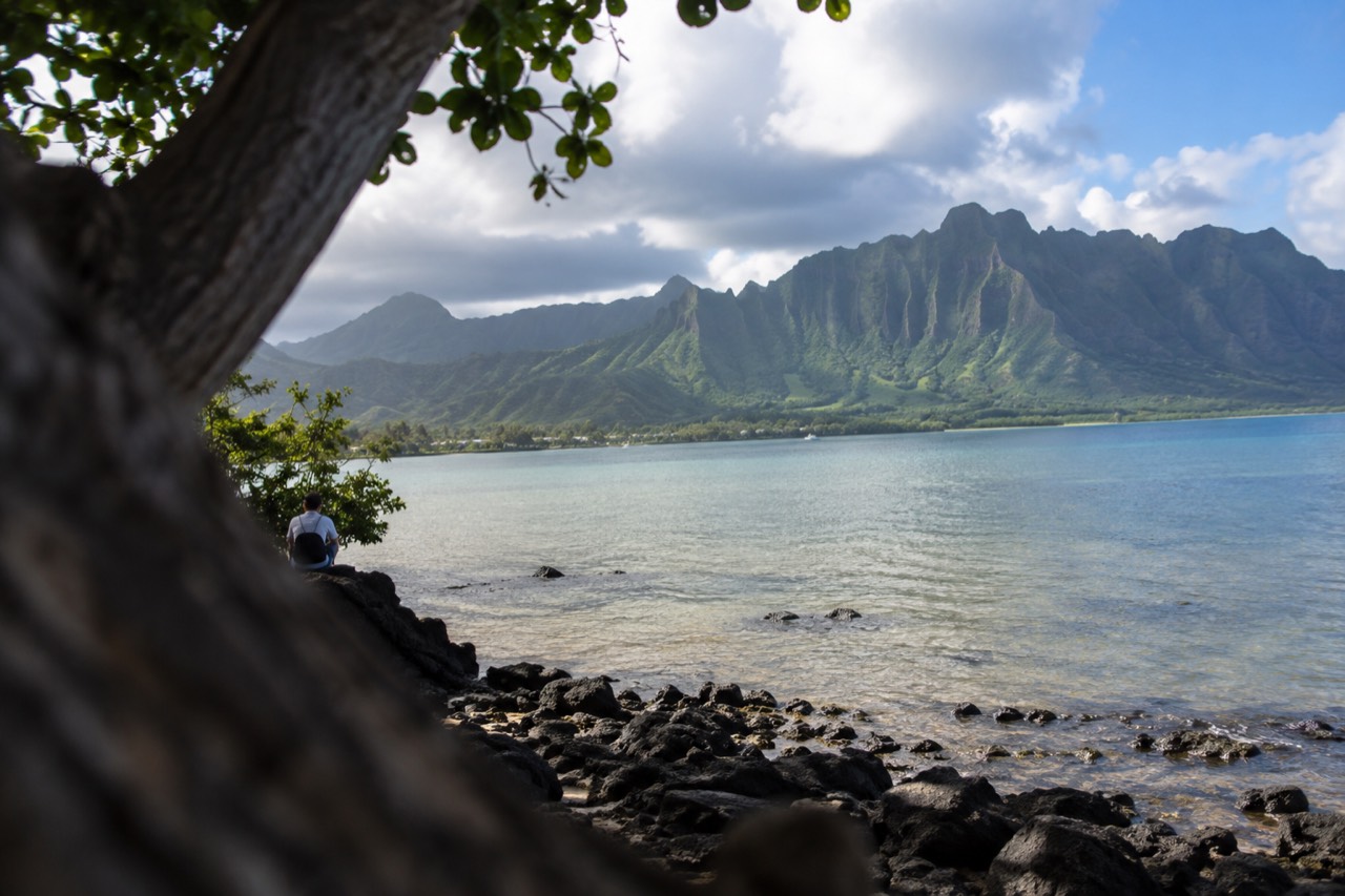 A view of Oahu's windward coast with green ridges meeting a calm blue bay